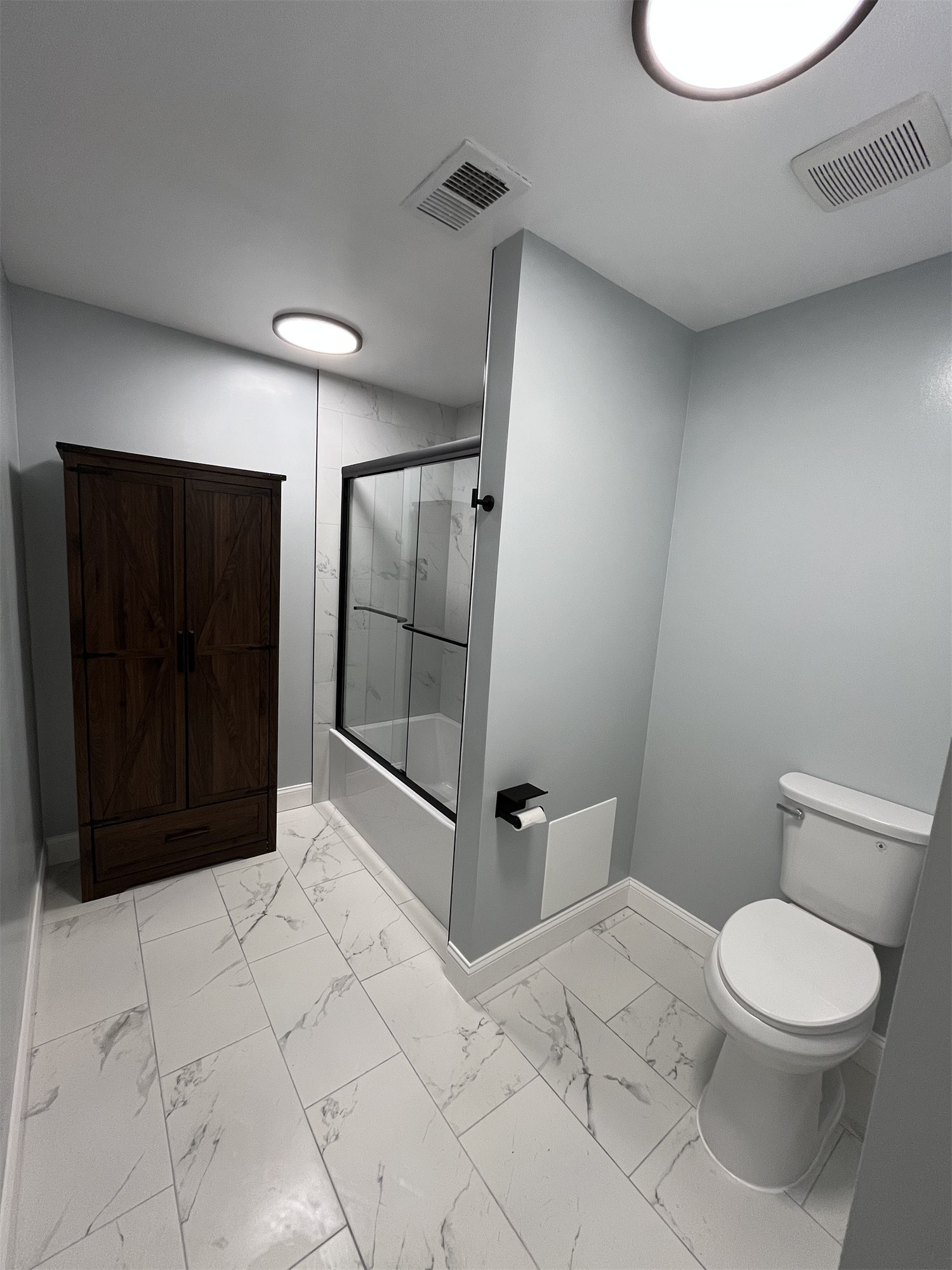 Completed bathroom showing a tiled shower beside a dark vanity