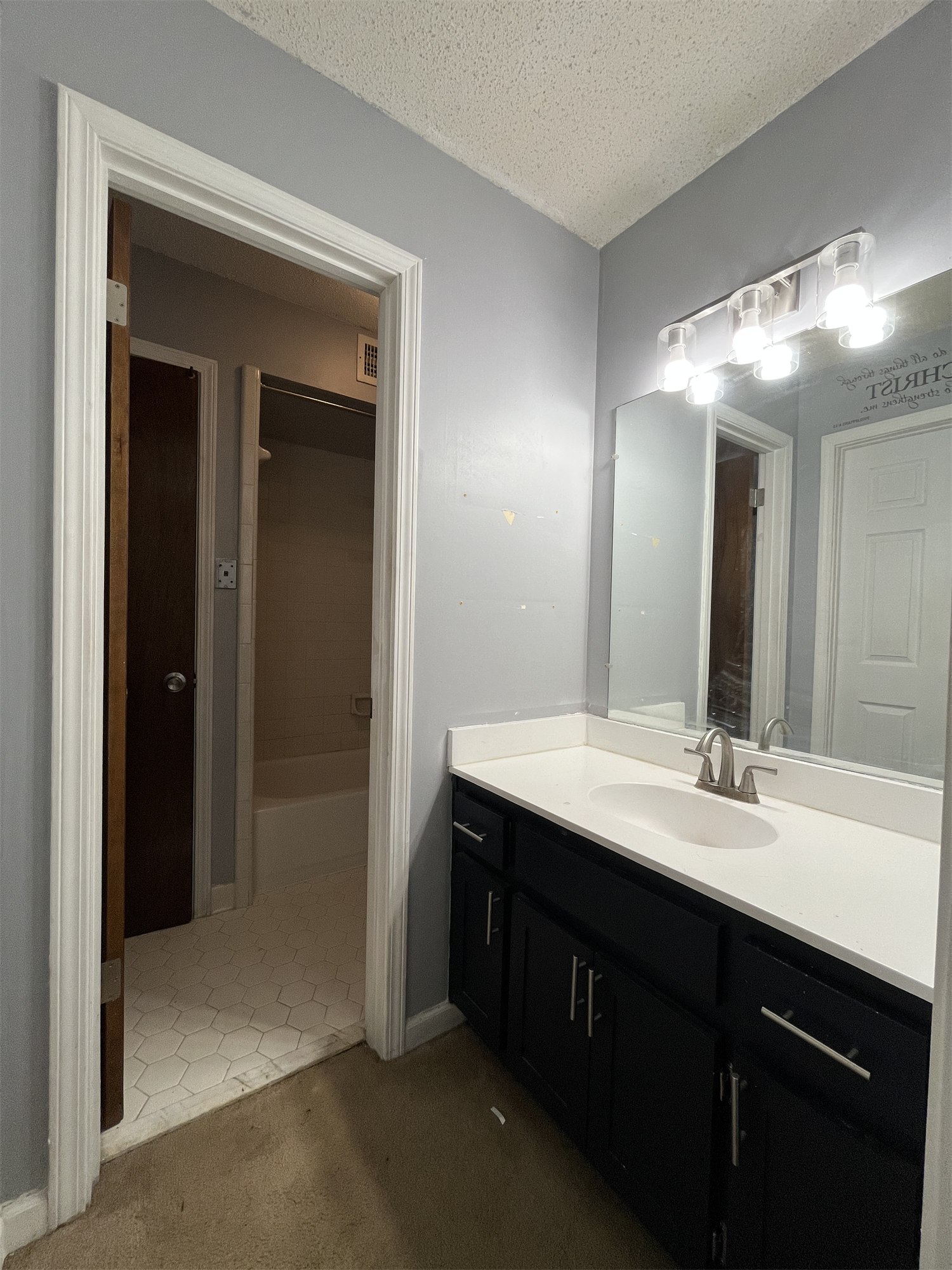 Angela bathroom before remodeling with a dark vanity, open doorway, and older finishes