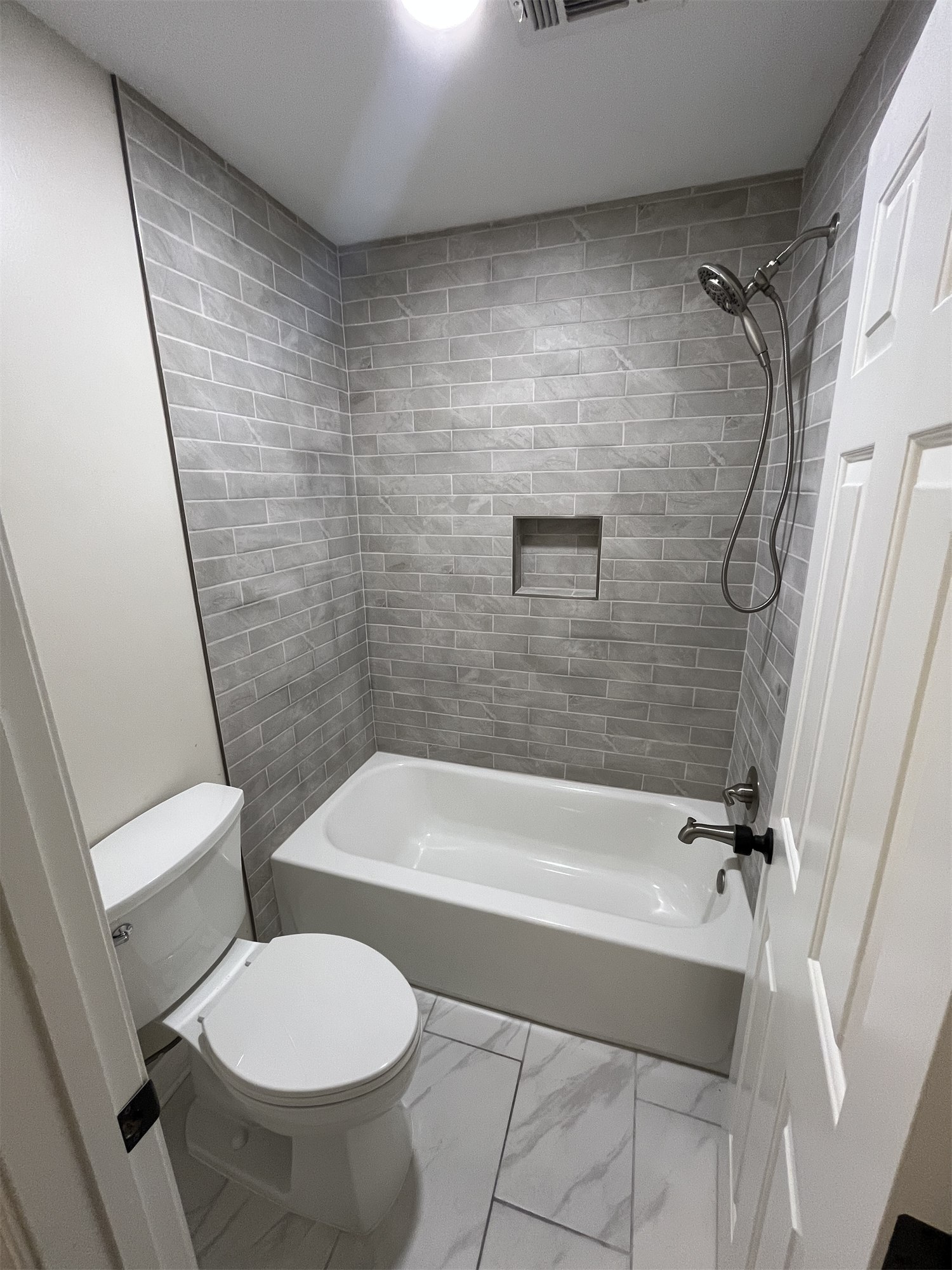 Completed bathroom with a gray tiled shower and bathtub
