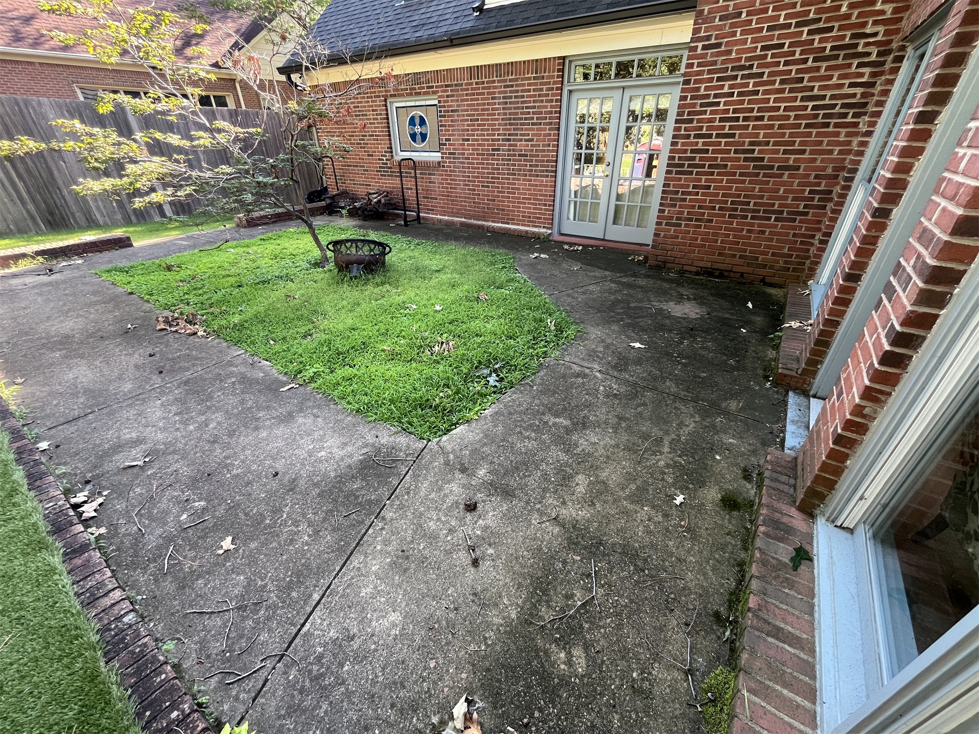 Concrete patio and walkway before cleaning beside a brick house